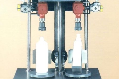 Macchinario semiautomatico per il riempimento di bottiglie, dotato di due ugelli.