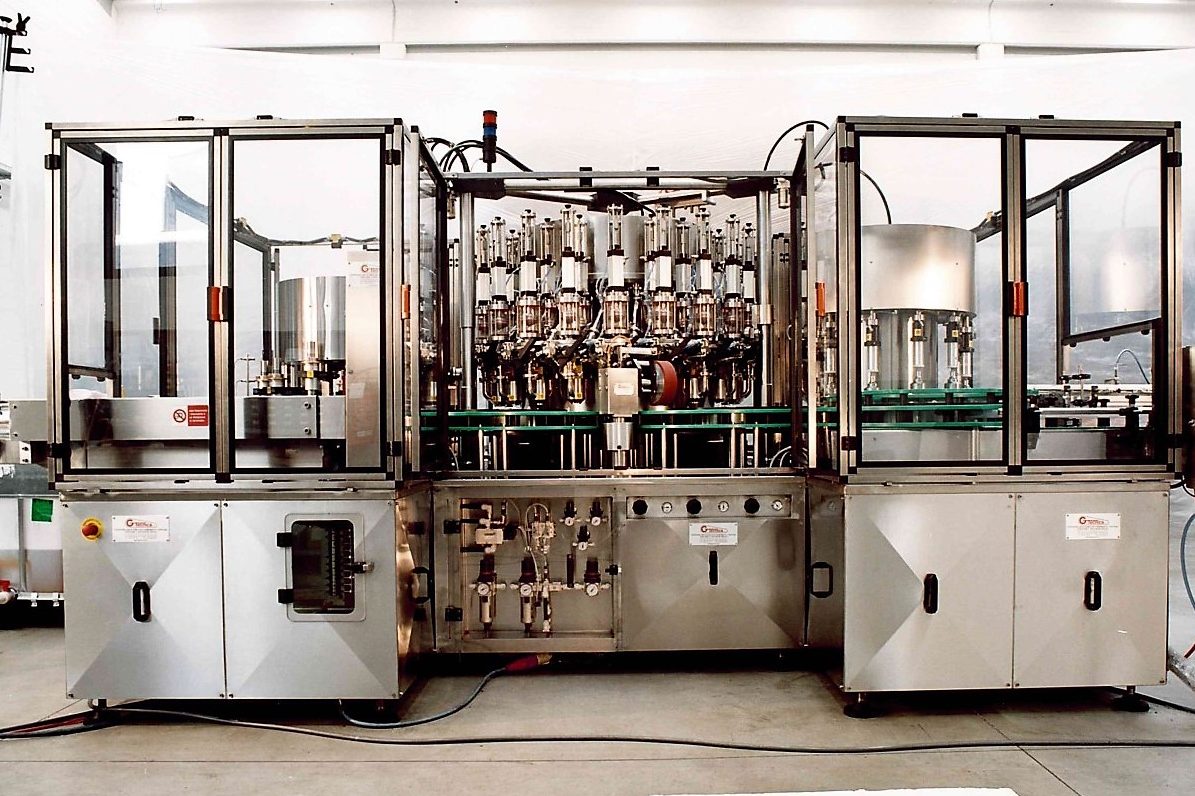 Macchinario industriale automatizzato per il riempimento di contenitori.