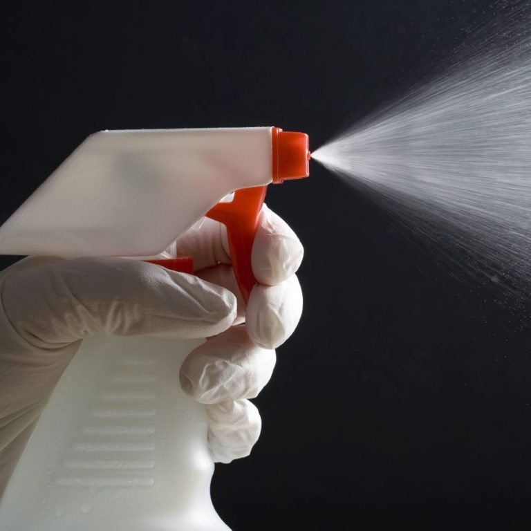 Mano d'uomo che tiene un flacone spray, che emette una nebbia sottile.